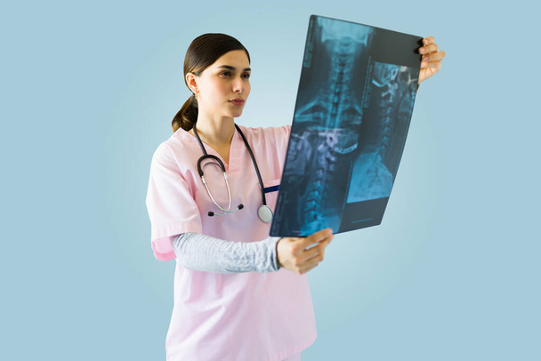 Female medical nurse checking a patient's x-ray and looking at broken bone against a studio background - Photo, Image