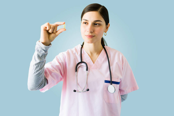 Professional female doctor holding a medicine pill and trying a new medical treatment  - Photo, Image