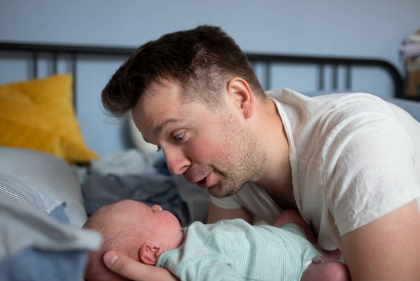Fiatal apa időt tölt újszülött kislányával az ágyban. - Fotó, kép