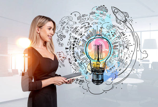 Smiling attractive businesswoman is standing near colourful sketch with light bulb, rocket, pie and bar diagram, cloud data. Office in background. Concept of imagination, inspiration for creative idea - Foto, Imagen
