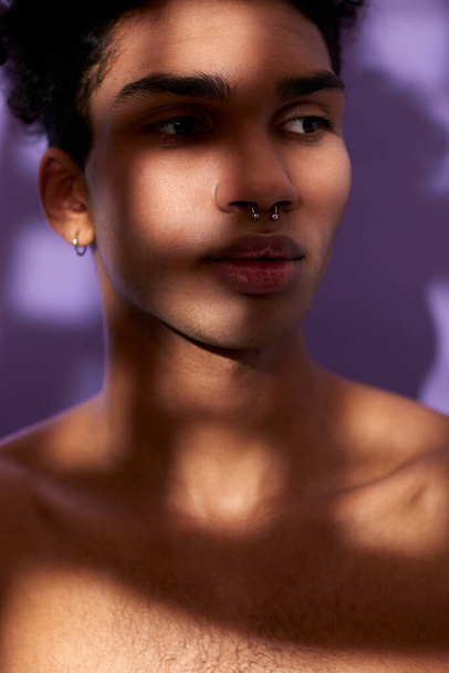 Verticale portrait of sensual young man in shadows. Sensitive hispanic model on purple background - Photo, Image