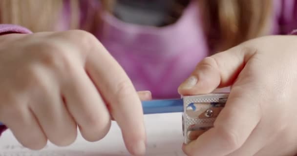 Close-up da mão de uma menina afia um lápis azul. A criança aguça um lápis.  - Filmagem, Vídeo