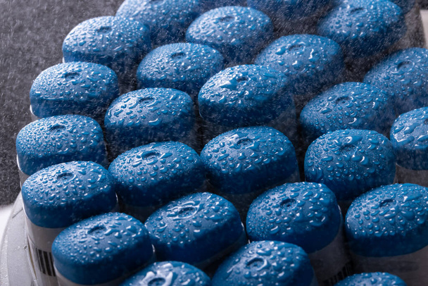 Many blue plastic caps under desinfection spray. - Photo, Image