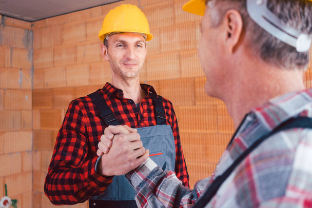 Männlicher Bauingenieur und Bauarbeiter beim Händeschütteln - Foto, Bild