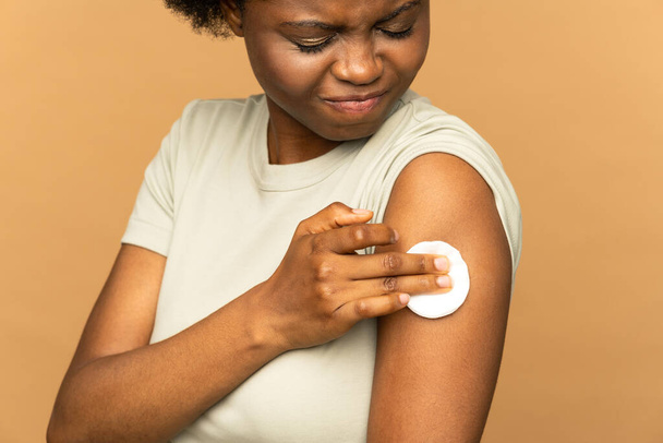 Mujer africana vacunada que muestra brazo con almohadilla de algodón después de la dolorosa inyección de vacuna para la hepatitis - Foto, imagen