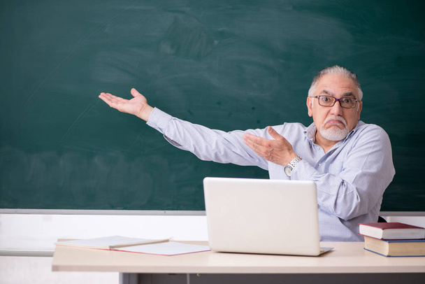 Öreg férfi tanár a zöld tábla előtt - Fotó, kép