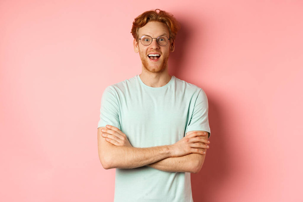 Portret wesołego Europejczyka w okularach zachwycony aparatem fotograficznym, zobacz interesującą promocję, stojący rozbawiony na różowym tle - Zdjęcie, obraz
