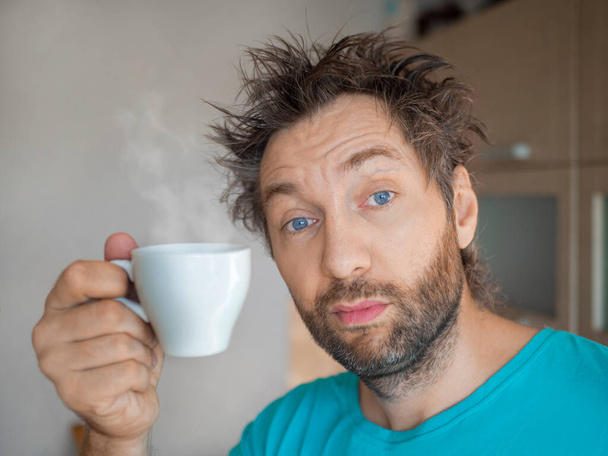 Портрет смешного человека после пробуждения с чашкой горячего кофе или чая. - Фото, изображение