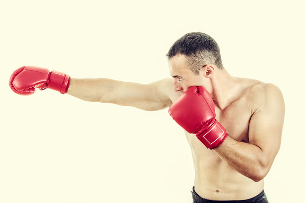 Muscular man wearing red boxing gloves and punching  - Фото, зображення