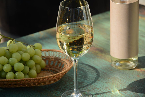 Tahta masada üzümlü bir bardak beyaz şarap. Beyaz şarap Riesling, beyaz üzümlerden. - Fotoğraf, Görsel