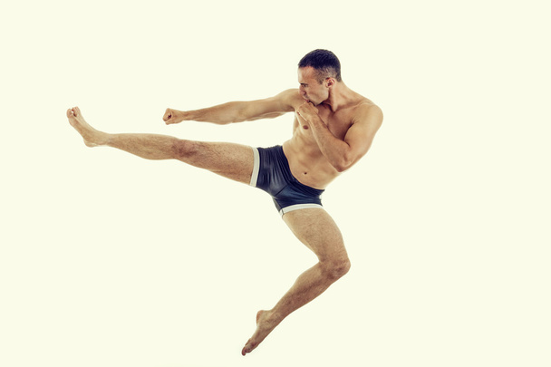 νεαρό μποξέρ μυϊκή μαχητής κάνει άσκηση με ένα τέλειο λάκτισμα - Φωτογραφία, εικόνα