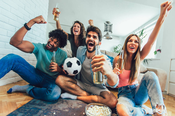 Skupina přátel sleduje fotbal doma a oslavuje vítězství. - Fotografie, Obrázek