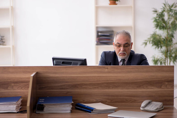 Aged male employee sitting at workplace - Foto, Bild