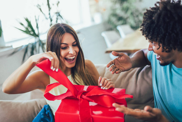 Man giving a surprise gift to woman at home - Fotó, kép