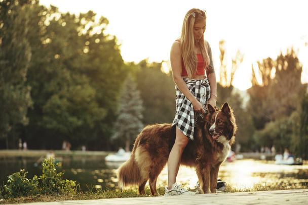 Border Collie σκυλί σε μια βόλτα στο πάρκο με τη γυναίκα ιδιοκτήτη του - Φωτογραφία, εικόνα
