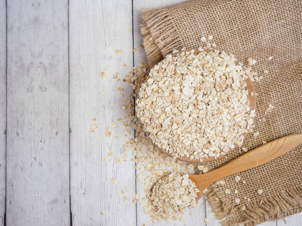 oatmeal in a wooden bowl and spoon on a wooden table close-up - Photo, image