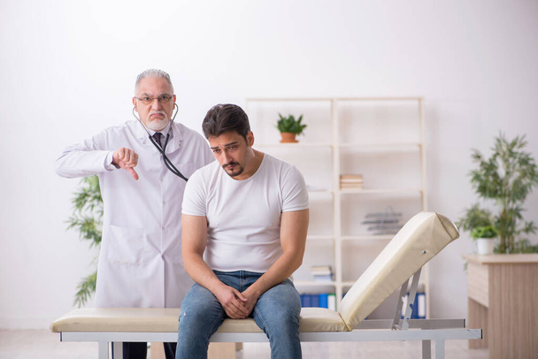 Jeune patient de sexe masculin visitant un vieux médecin - Photo, image