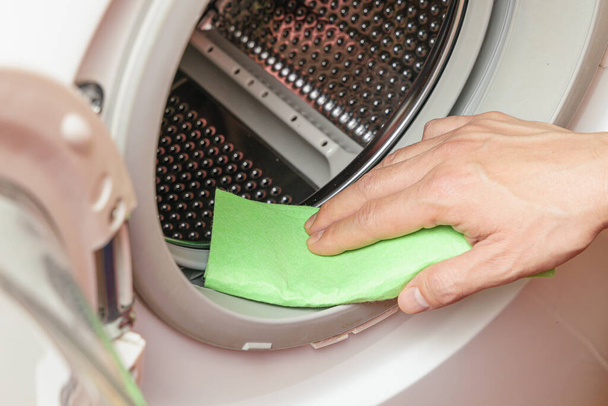 Ręczne czyszczenie wilgoci z bębna pralki. Koncepcja konserwacji pralki - Zdjęcie, obraz