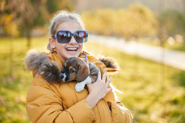 Girl spending free time with favourite puppy in park. - Фото, изображение