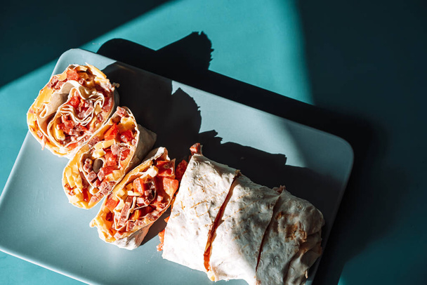 Krájená shawarma na čtvercové modré desce na azurovém pozadí - Fotografie, Obrázek