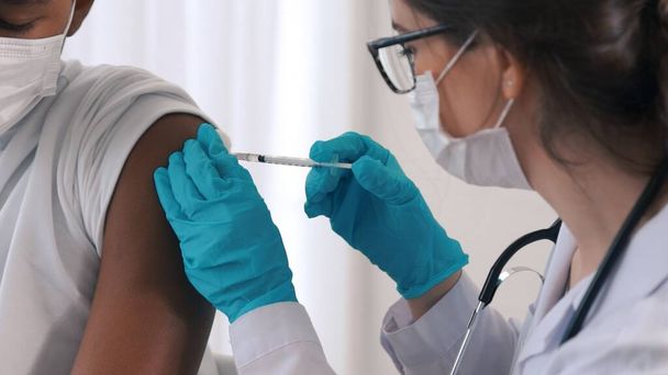 Un jeune homme consulte un médecin habile à l'hôpital pour se faire vacciner - Photo, image