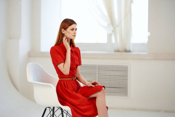 Nainen punaisessa mekossa istuu tuolilla glamouria poseeraa - Valokuva, kuva