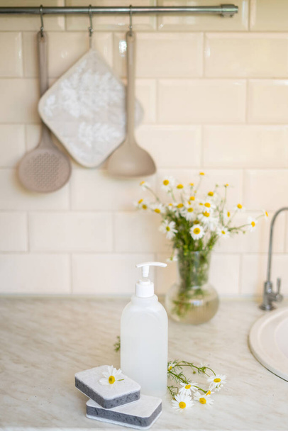 Ekologiczne nietoksyczne mydło do mycia naczyń z kwiatami rumianku, czyste białe talerze. Wysokiej jakości zdjęcie - Zdjęcie, obraz