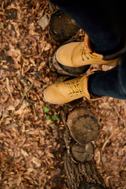 Horní pohled žena stojící s turistickými horskými botami na podzim listí a dřevo pozadí, relaxační, místní cestování, duševní zdraví. Kopírovat prostor - Fotografie, Obrázek