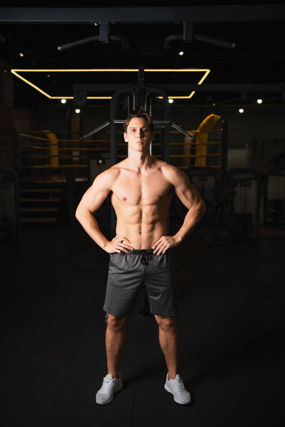 shirtless athletic man standing with hands on hips in sports center - Photo, Image