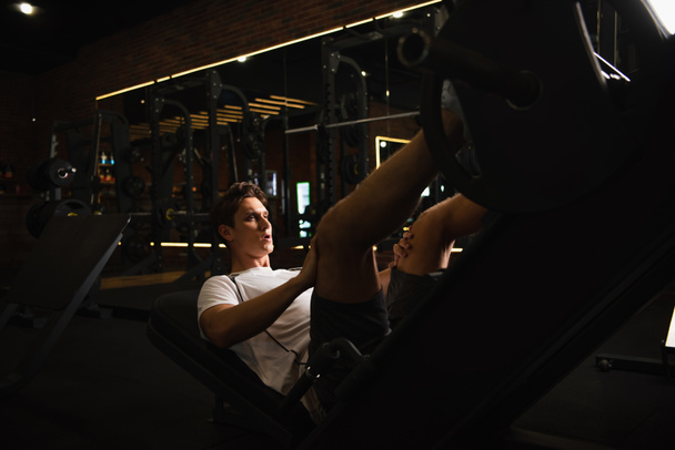 αθλητικός άνθρωπος που εργάζονται για την επέκταση πόδι μηχανή άσκησης στο αθλητικό κέντρο - Φωτογραφία, εικόνα