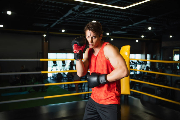 Sportlicher Mann mit Boxhandschuhen beim Training im Sportzentrum - Foto, Bild