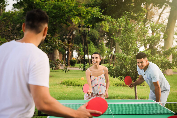 Friends playing ping pong outdoors on summer day - Fotó, kép
