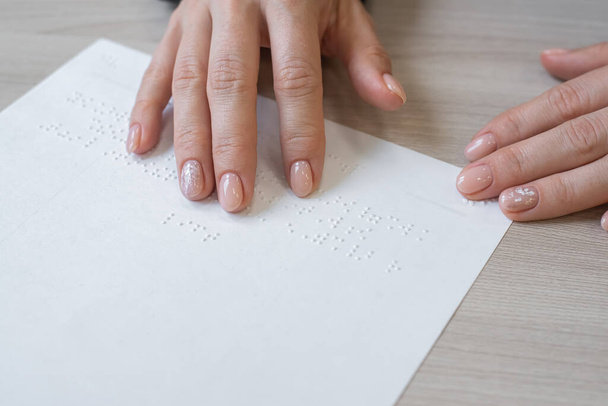 Close-up woman reads the text to the blind. Womans hands on paper with braille code. - Foto, imagen