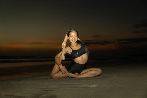Sunset Beach jóga. Egy nő, aki Eka Pada Rajakapotasanát gyakorolja, egy lábú Galamb Király Pózt. A mellkasnyitó javítja a légzést. Öngondoskodás. Jóga elvonulás. Másold a helyet. Seminyak strand, Bali - Fotó, kép