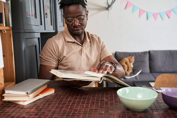 Man reading his favorite book while sitting at the table at home - Valokuva, kuva