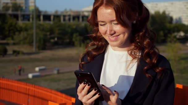 Positiivinen nainen mustat kynnet tekstejä puhelimessa kadulla - Materiaali, video