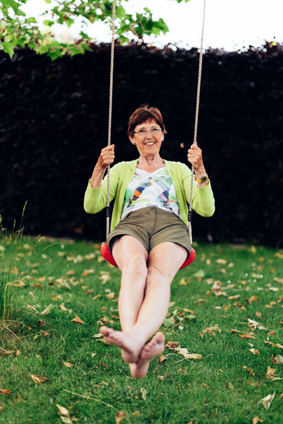 positive smiling healthy elderly woman plays on the swing - Foto, imagen
