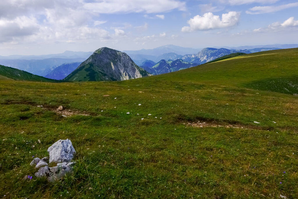 piedra blanca en la hierba verde en la cima de una montaña con maravillosas vistas al paisaje natural - Foto, Imagen