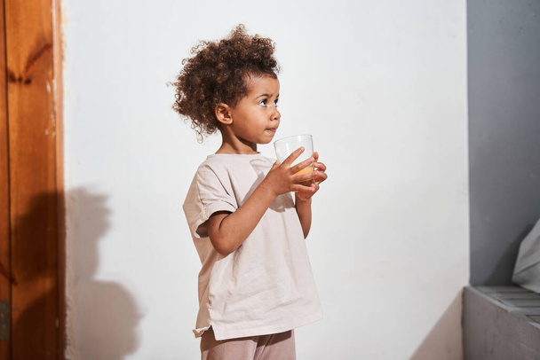 Multiracial girl looking away while drinking juice at the morning - Foto, Bild