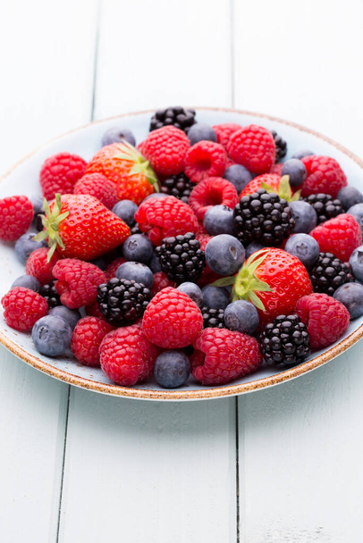 Fresh berries salad in a plate on a  wooden background. Flat lay, top view, copy space. - Фото, зображення