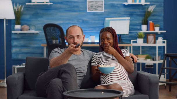 POV de pareja interracial con embarazo viendo televisión - Foto, imagen