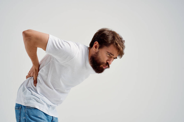 emocional hombre en un blanco camiseta estrés medicina dolor de espalda estudio tratamiento - Foto, Imagen