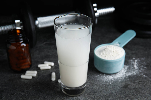 Amino acid shake, powder, pills and dumbbell on grey table - Fotó, kép