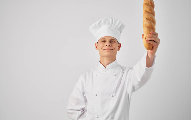 a man in a chefs uniform holding a loaf baker preparing food - Φωτογραφία, εικόνα