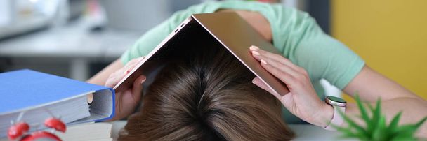 Zmęczona młoda kobieta leży na stole na głowie z laptopem - Zdjęcie, obraz