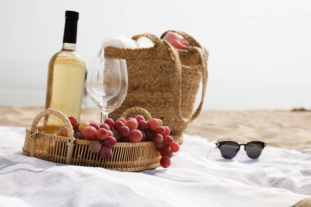 Bag, blanket, wine and other stuff for beach picnic on sandy seashore - Photo, Image