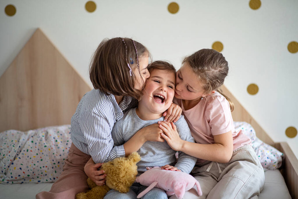 Portrait of three girls sisters indoors at home, kissing. - Foto, imagen