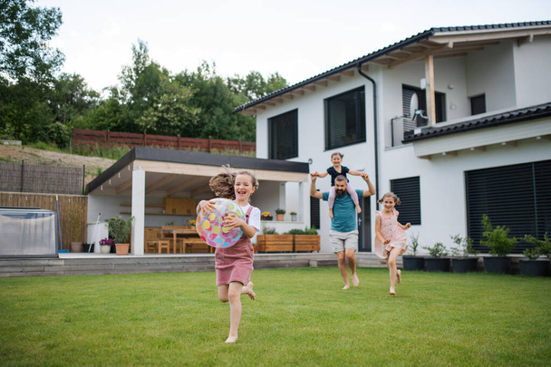 Padre con tres hijas jugando al aire libre en el patio trasero, corriendo. - Foto, Imagen