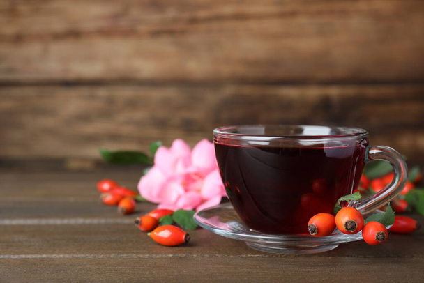 Aromatic rose hip tea and fresh berries on wooden table, space for text - Fotografie, Obrázek