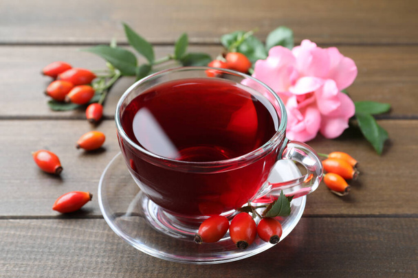Aromatic rose hip tea and fresh berries on wooden table - Foto, Imagem